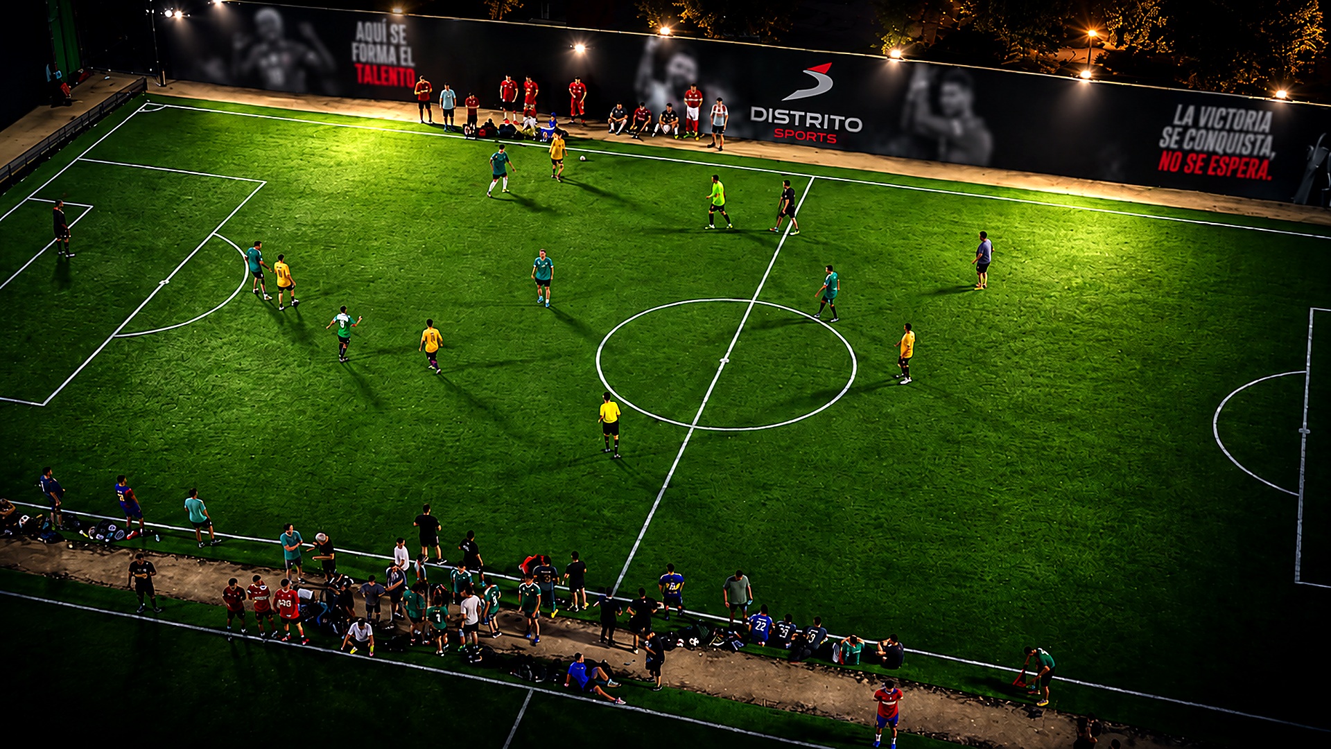 Partido nocturno en las canchas de Distrito Sports frente al mural principal